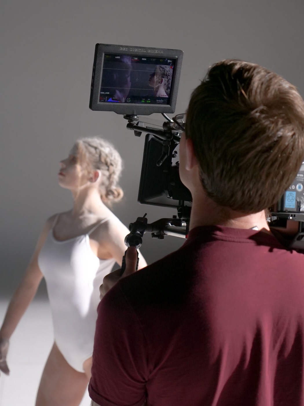 Camera operator filming a dancer, seen from behind