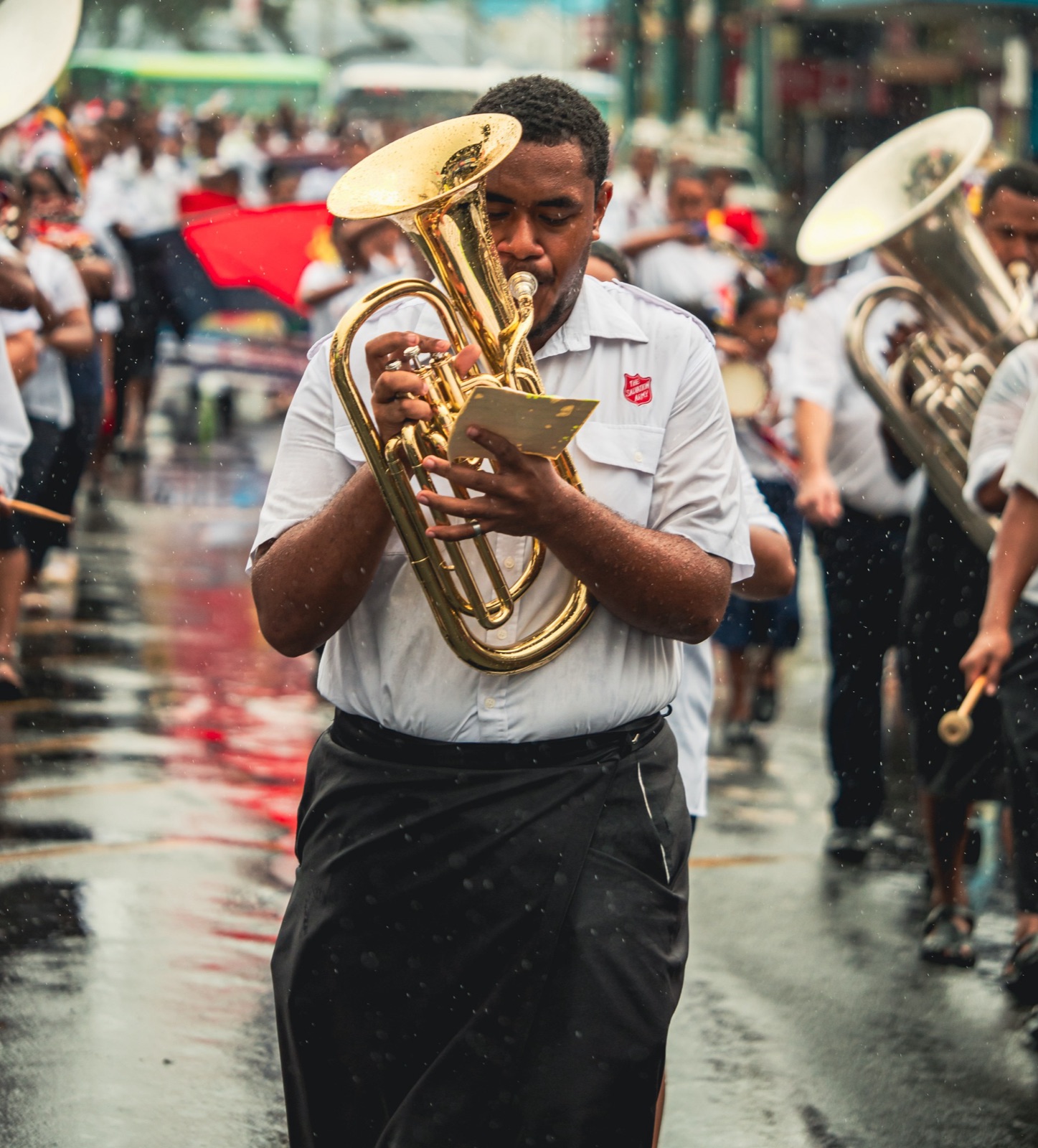 Brass band musician playing in the rain during a street parade