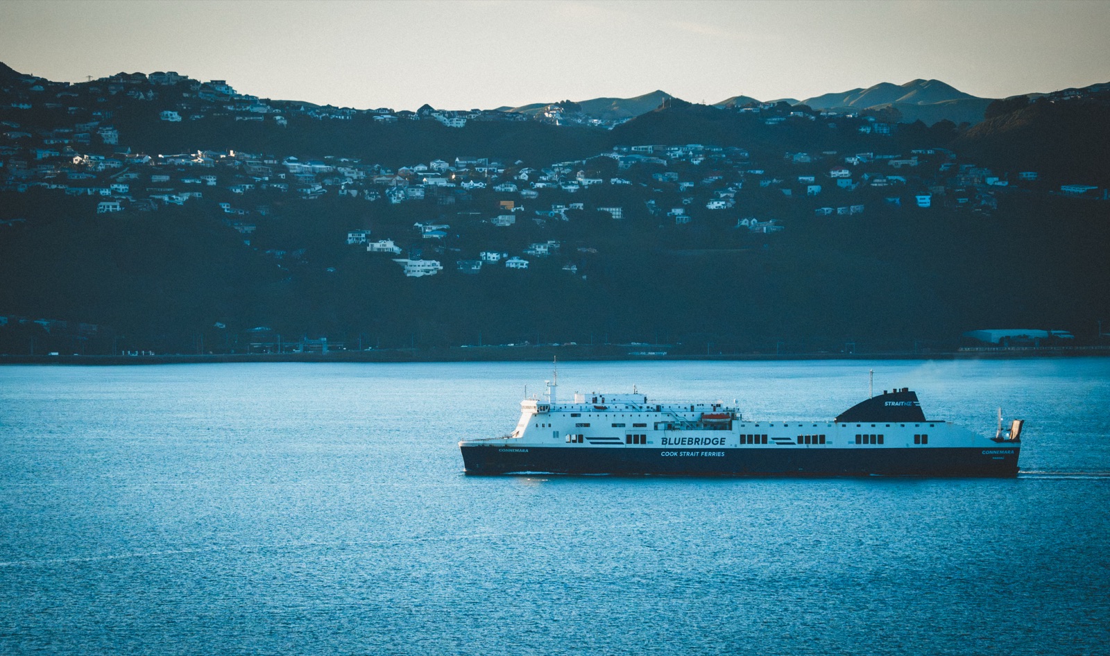 Interislander ferry crossing a dark blue harbour at dusk