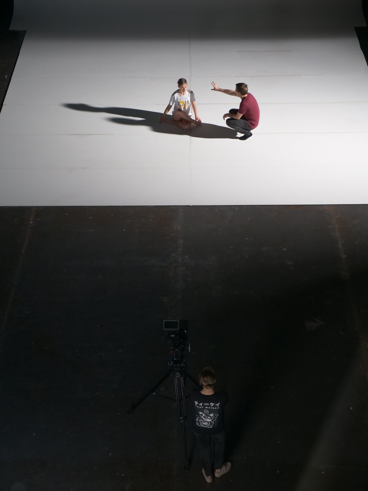 Overhead view of a director and dancer on a white studio cyclorama
