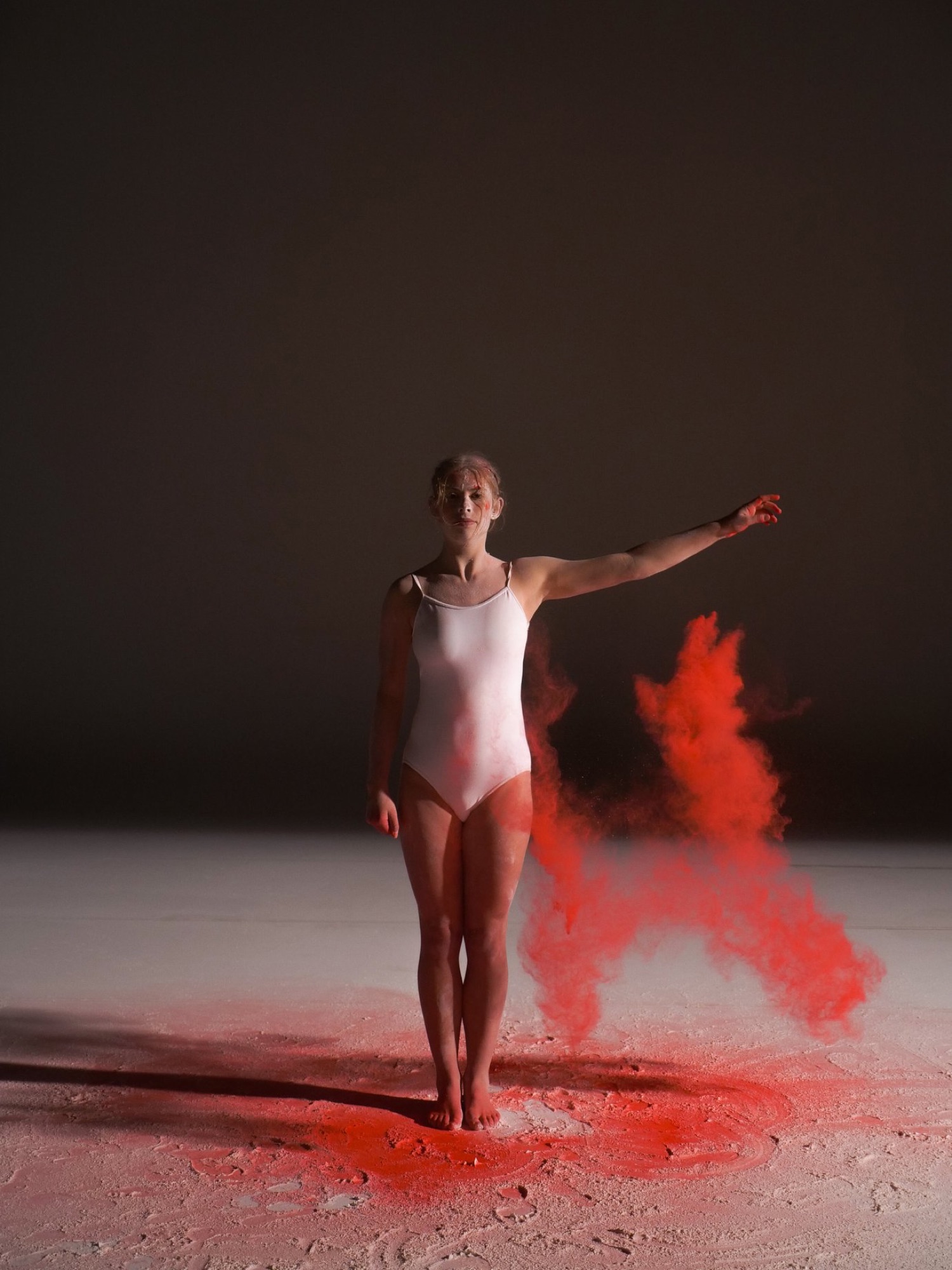 Dancer mid-turn in a burst of red pigment, studio shoot